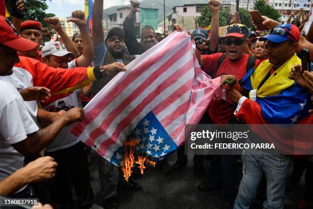 Supporters of the Venezuelan government burn a makeshift US flag during a rally against US sanctions in Caracas on August 10, 2019. - Earlier this...