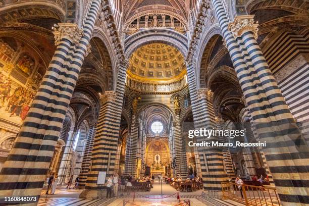 people walking in the interior of the siena cathedral at the city of siena in tuscany, italy. - marble cathedral stock pictures, royalty-free photos & images