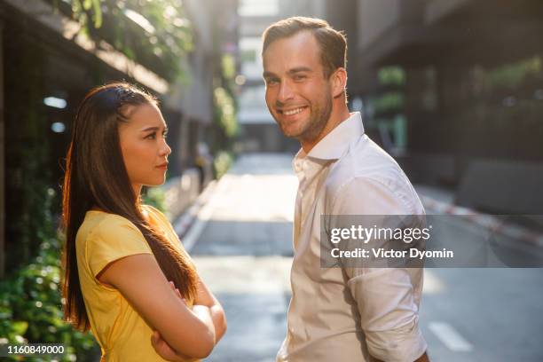 asian girl and caucasian man together on the street - sneering stock pictures, royalty-free photos & images