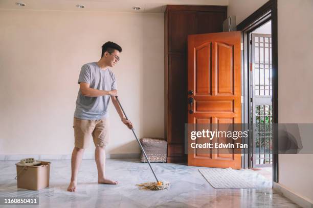 an asian chinese male mopping living room floor during weekend - mop stock pictures, royalty-free photos & images