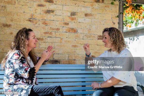 two deaf women having a signed conversation. - brisbane sign stock pictures, royalty-free photos & images