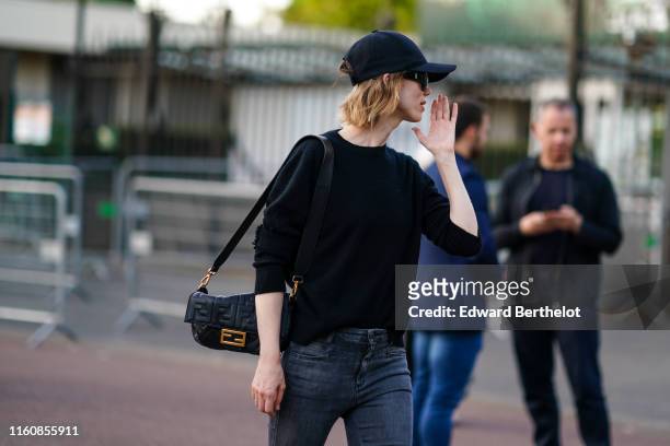 Anya Ziourova wears Saint Laurent sunglasses, a black cap, a black sweater, a black Fendi bag, jeans, outside Miu Miu Club 2020, on June 29, 2019 in...