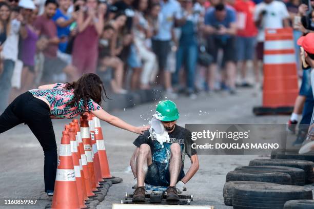 Man competes in a downhill-kart racing known as "Mundialito de Rolima do Abacate" as a cake is smashed against him as part of obstacles from...