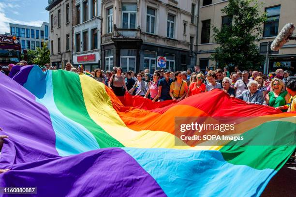 Huge rainbow flag held by several people during the parade. Antwerp Pride commemorates and celebrates the long journey forwards acceptance and equal...