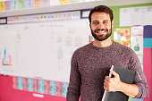 Portrait Of Male Elementary School Teacher Standing In Classroom