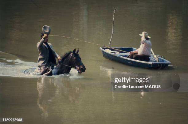 Acteur Jean Rochefort traverse une étendue d'eau à cheval et salue un pêcheur dans une barque dans une scène du film 'Un éléphant ça trompe...