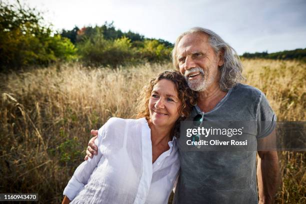 happy mature couple embracing in a field - long hair nature stock-fotos und bilder