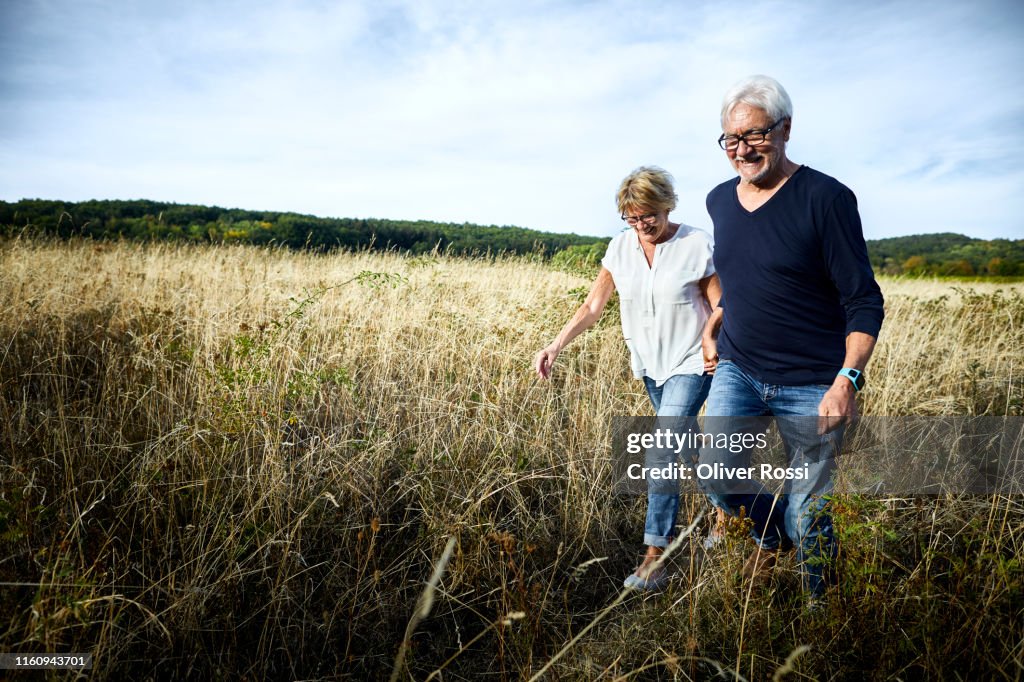 Happy mature couple walking in a field