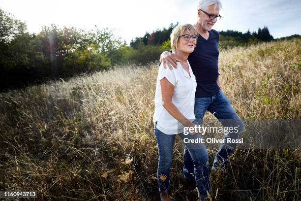 mature couple walking in a field - mature adult couple stockfoto's en -beelden