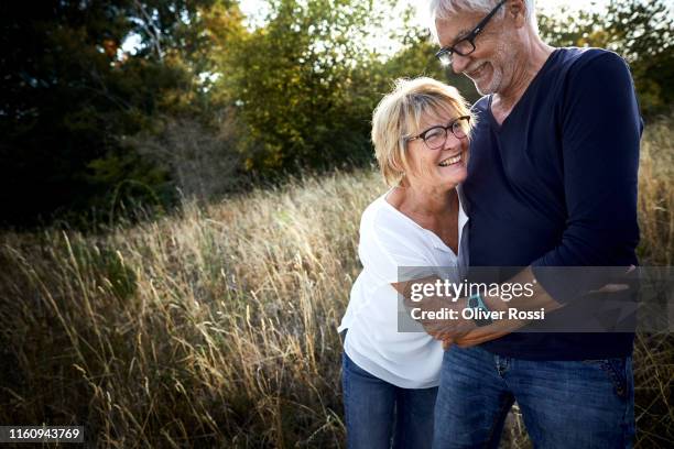 happy mature couple embracing in a field - old man laughing and glasses stock pictures, royalty-free photos & images