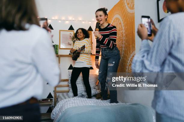 two teens singing and playing guitar - girls sleepover stock-fotos und bilder