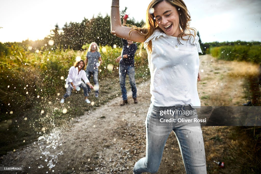 Happy woman is being splashed on dirt road in the countryside