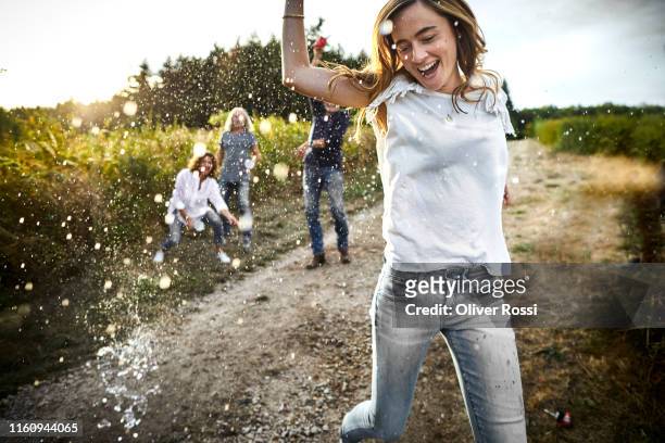 happy woman is being splashed on dirt road in the countryside - vitality stock-fotos und bilder