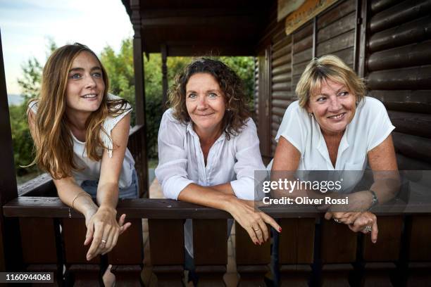 portrait of three women leaning on balcony of a log cabin - age contrast stock pictures, royalty-free photos & images