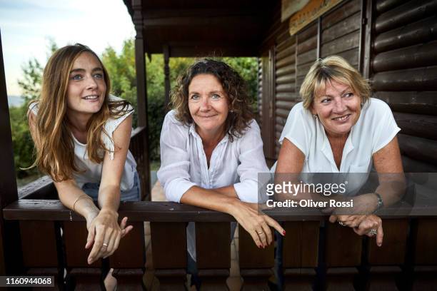 portrait of three women leaning on balcony of a log cabin - família de duas gerações imagens e fotografias de stock