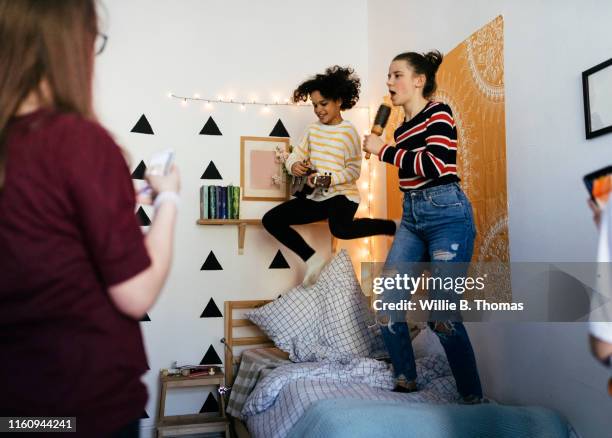 cheerful girls singing into hairbrushes at slumber party - 13 years old girl in jeans stock pictures, royalty-free photos & images