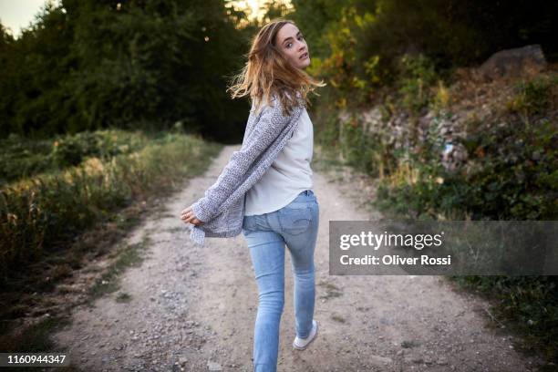 woman walking on a dirt track in the countryside turning round - achtervolgen stockfoto's en -beelden