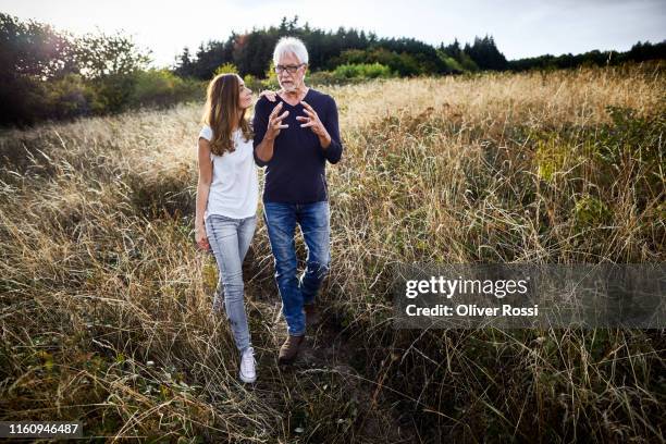 father walking with adult daughter at a field in the countryside - father and grown up daughter stock-fotos und bilder