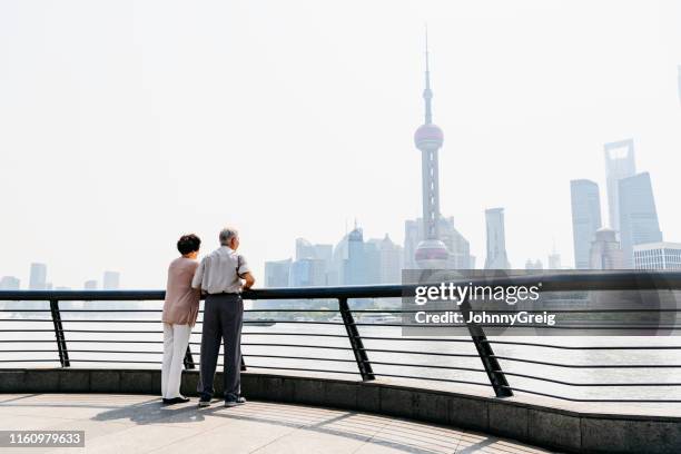 personas de la tercera edad chinas mirando al otro lado del huangpu en pudong skyline - vista de la tierra fotografías e imágenes de stock