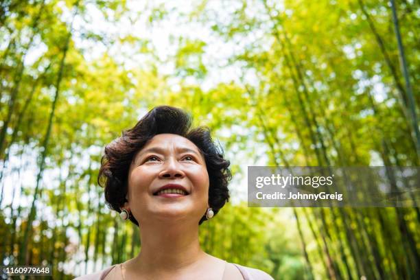 aktive senior in china, die durch denbambushain läuft - chinese woman outside walking stock-fotos und bilder