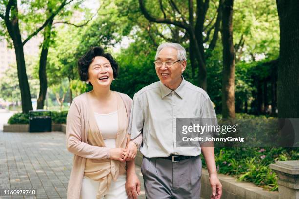 lighthearted chinese seniors walking at a shanghai park - asian senior couple stock pictures, royalty-free photos & images