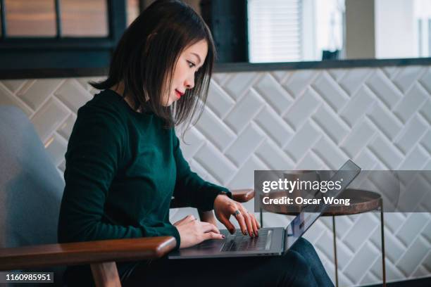 smiling, confident, modern businesswoman checking email at laptop in office - portrait of cool creative businesswoman at office stock-fotos und bilder