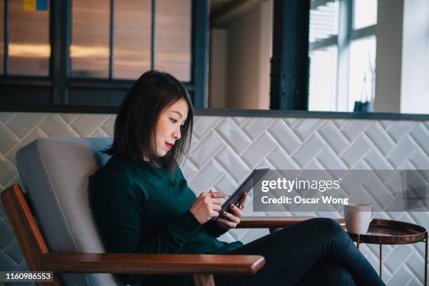 smiling, confident, modern businesswoman checking email at digital tablet in office - lounge chair bildbanksfoton och bilder