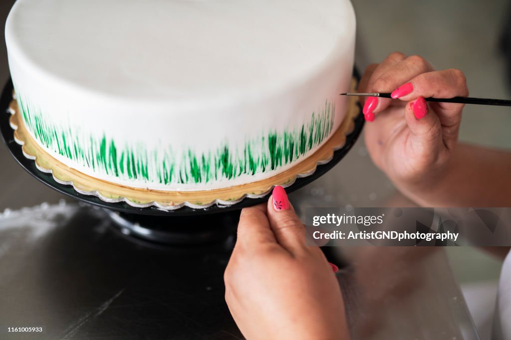 Female confectioner hands making cake.