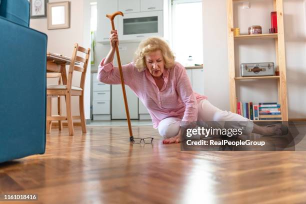 hjälplös pensionerad kvinna med blont hår som sitter på golvet hemma. de risker som kommer med att bli äldre. - falla bildbanksfoton och bilder