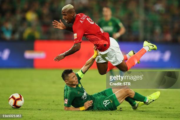 Guangzhou Evergrande's Anderson Talisca tumbles as he crashes into Beijing Guoan's Yu Dabao during their Chinese Super League football match in...
