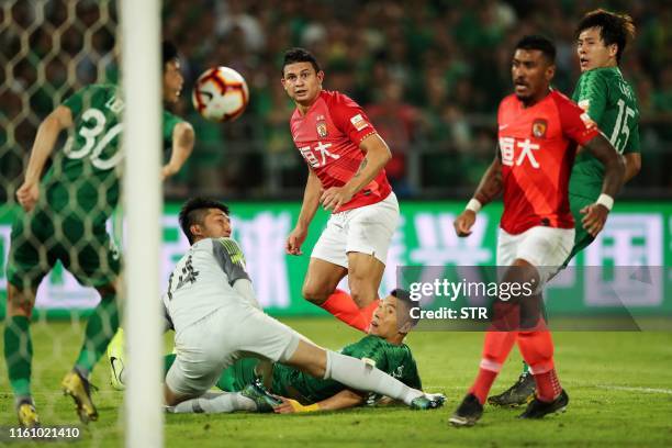 Guangzhou Evergrande's Elkeson watches as Beijing Guoan's goal keeper Zou Dehai fails to stop a goal during their Chinese Super League football match...