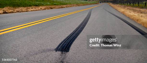 country road through rolling hills - skid marks fotografías e imágenes de stock