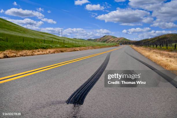 country road through rolling hills - skid marks stock pictures, royalty-free photos & images