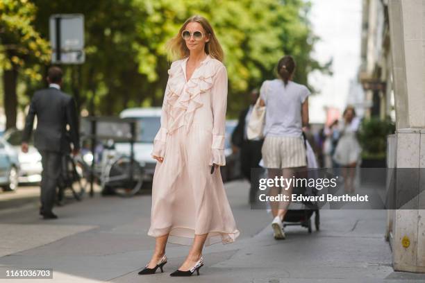 Guest wears sunglasses, a pale pink frilly flowing dress, black Dior J'Adior pointy heeled slingback pumps, outside Dior, during Paris Fashion Week...