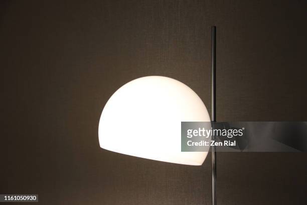 an illuminated semi-circular lamp shade on a floor lamp - floor lamp stock pictures, royalty-free photos & images