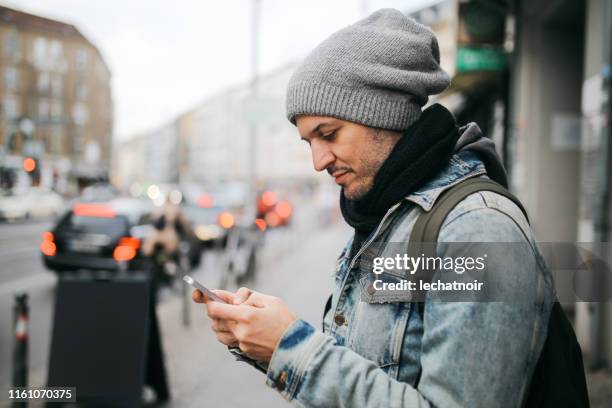 young man texting in berlin - denim jacket stock pictures, royalty-free photos & images