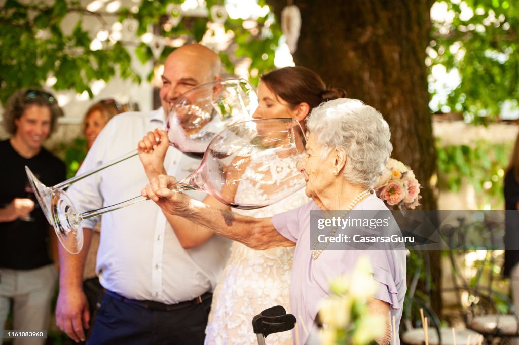 Bruid en haar moeder in de wet het drinken van wijn uit grote Wineglass bij Wedding Celebration