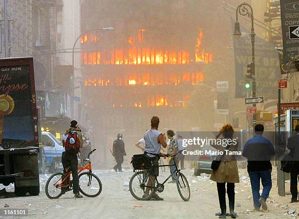 People walk in the street in the area where the World Trade Center buildings collapsed September 11, 2001 after two airplanes slammed into the twin...