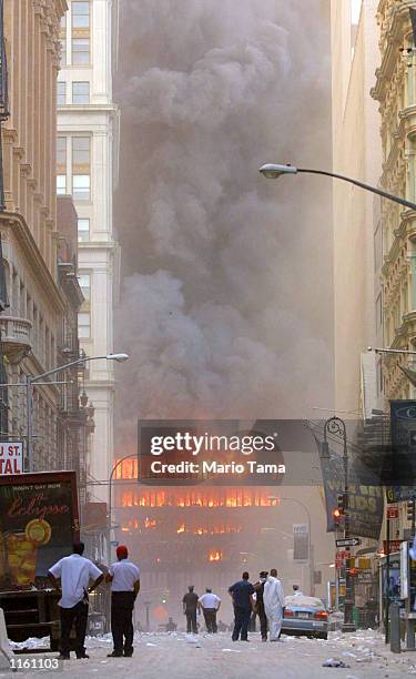 People walk in the street in the area where the World Trade Center buildings collapsed September 11, 2001 after two airplanes slammed into the twin...