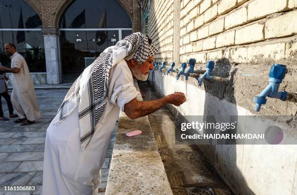Shiite Muslim man performs the ablution cleansing ritual before the start of Eid al-Adha prayers at a mosque in the central Iraqi shrine city of...
