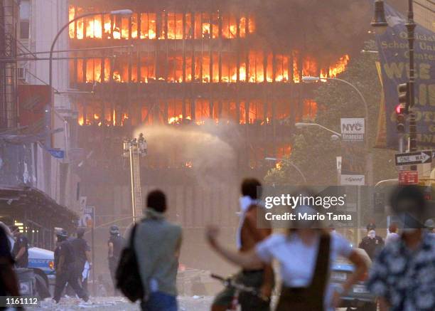 People walk in the street in the area where the World Trade Center buildings collapsed September 11, 2001 after two airplanes slammed into the twin...