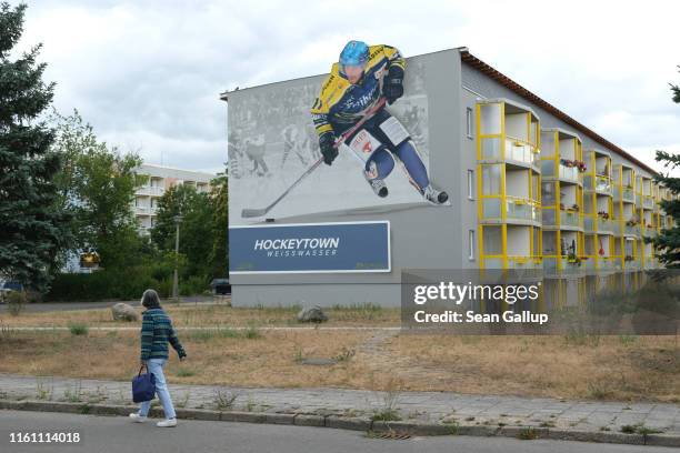 An elderly woman walks past a mural honoring the local ice hockey team on an apartment building on July 09, 2019 in Weisswasser, Germany....