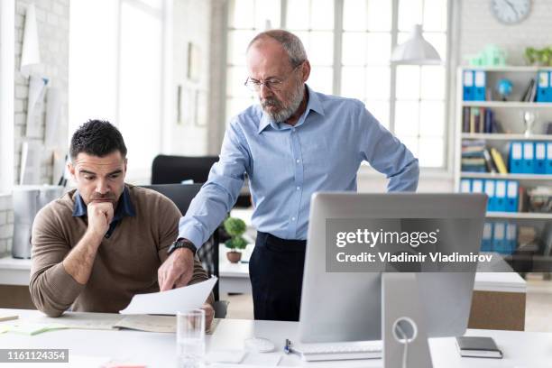 senior manager che spiega al collega qualcosa sul computer - ammonite foto e immagini stock