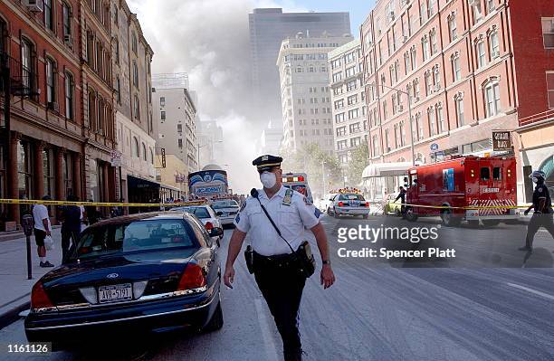 Police officer patrols in the street after the collapse of the World Trade Center towers September 11, 2001 in New York City after two airplanes...
