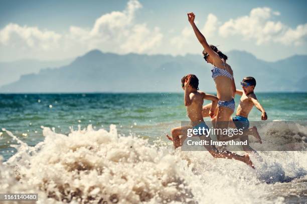 kinderen met extreme plezier lopen in zee - droplet sea summer stockfoto's en -beelden