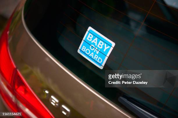 blue baby on board sticker in rear view window of car - car rear stock-fotos und bilder