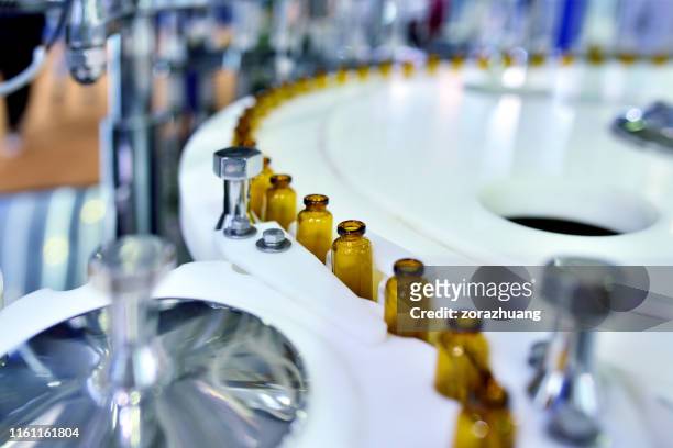 nahaufnahme der braunen glasflasche an der turntable production line - filling stock-fotos und bilder