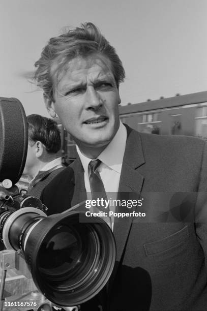 English actor Roger Moore , who plays Simon Templar in the Incorporated Television Company television series 'The Saint', pictured standing beside...