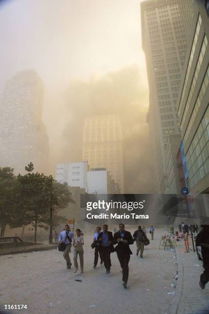 Civilians flee as a tower of the World Trade Center collapses September 11, 2001 after two airplanes slammed into the twin towers in an alleged...