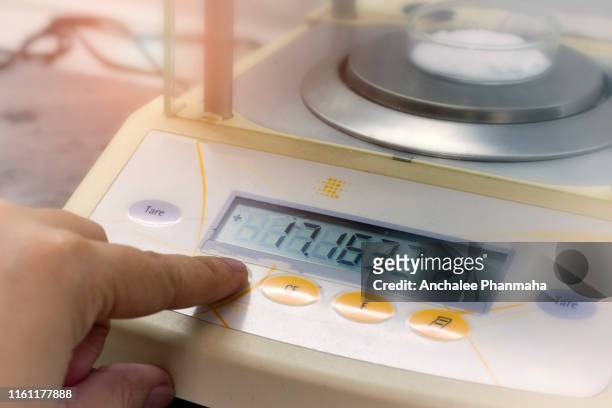 scientist is weighing the sample with electronic weighing scales (laboratory balance weighing) in chemical laboratory. - mass unit of measurement stock-fotos und bilder